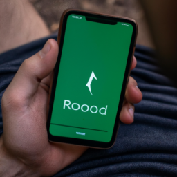 description: a person looking at their phone, with the robinhood app open on the screen.