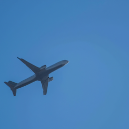 description: an airplane flying in the sky with a clear blue background.