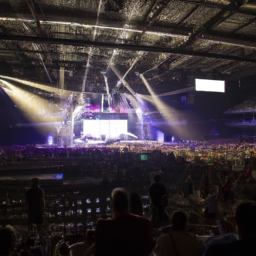 a large arena with bright lights illuminating the stage. the crowd is visible in the background, with people of all ages and backgrounds enjoying the entertainment.