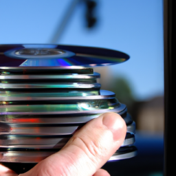 A close-up of a hand holding a stack of CDs with a bank in the background.