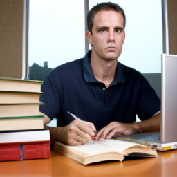 a person sitting at a desk with a laptop and a stack of books, looking focused and determined. they have a pen in their hand and a notepad open in front of them.